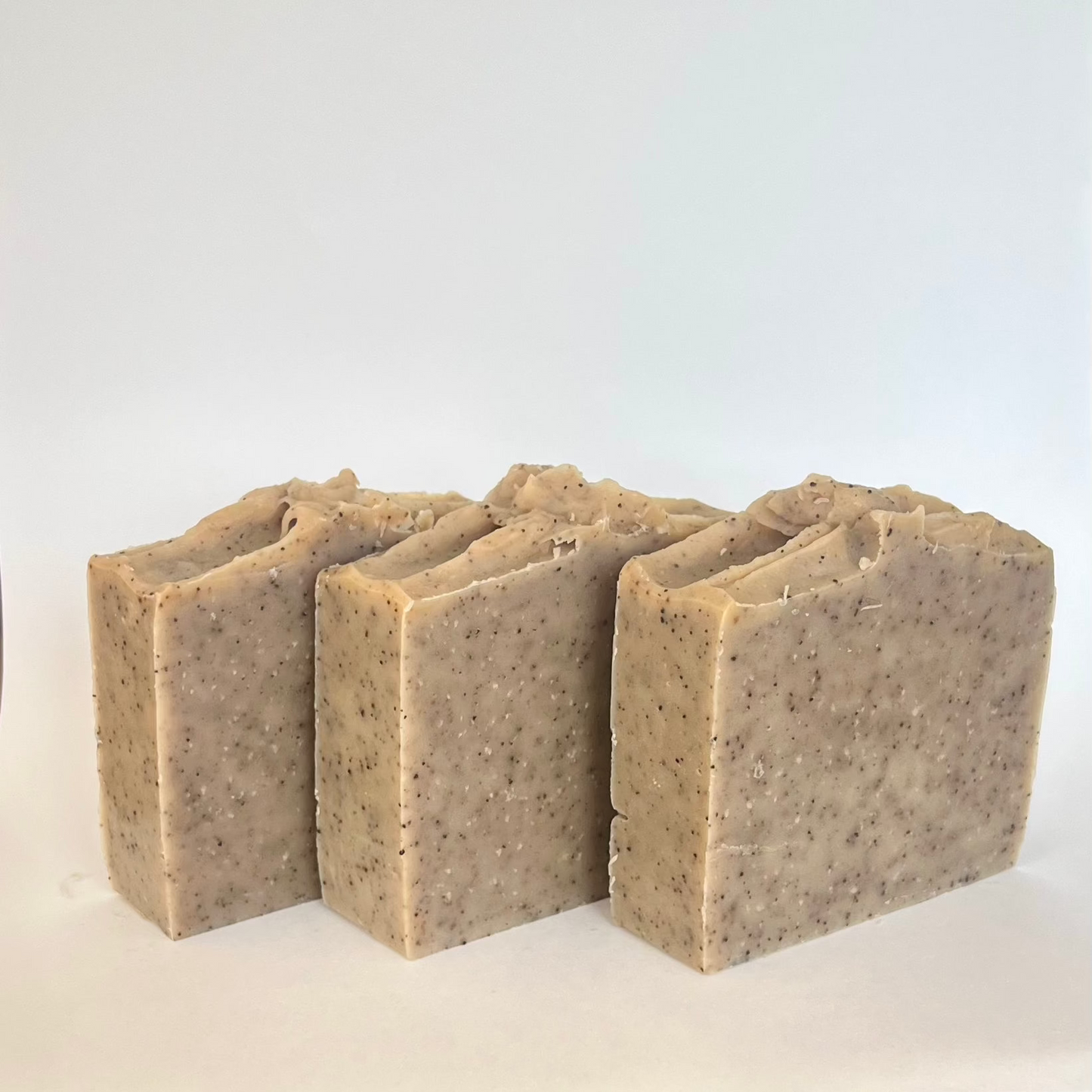 Vegan Garden Glow scrubzeep, handgemaakt met krachtige kleiën en koffiedeeltjes, verfrist en verzorgt ruwe handen na een dag hard werken, met een warme kruidige geur.